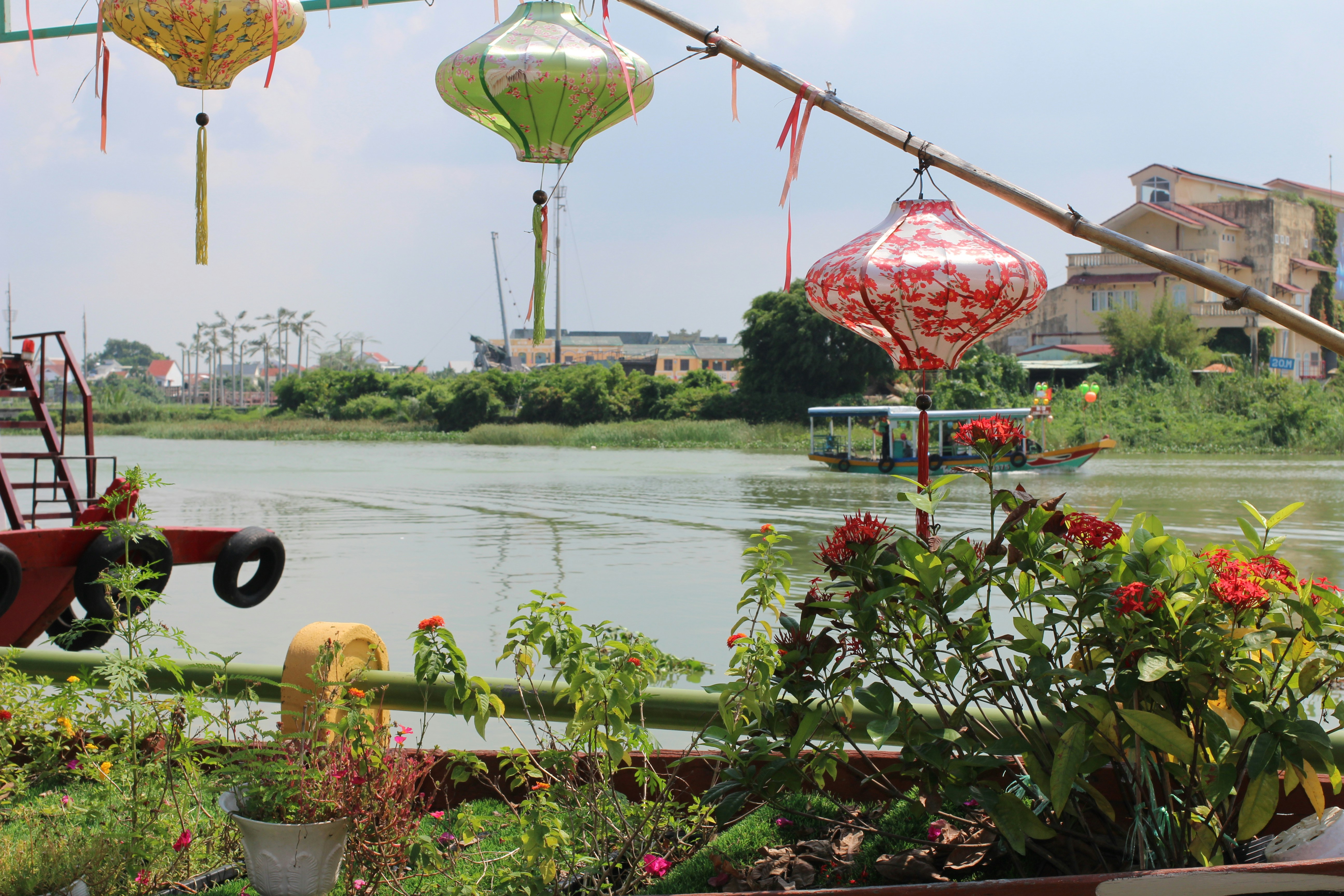 A bunch of lanterns hanging from a line over a body of water
