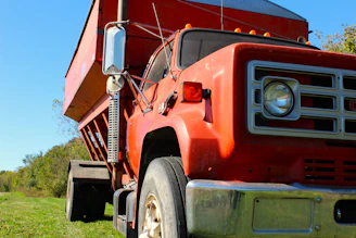 A red dump truck parked in a grassy field