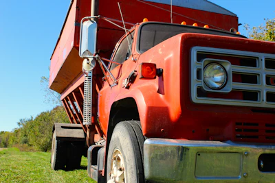 A red dump truck parked in a grassy field