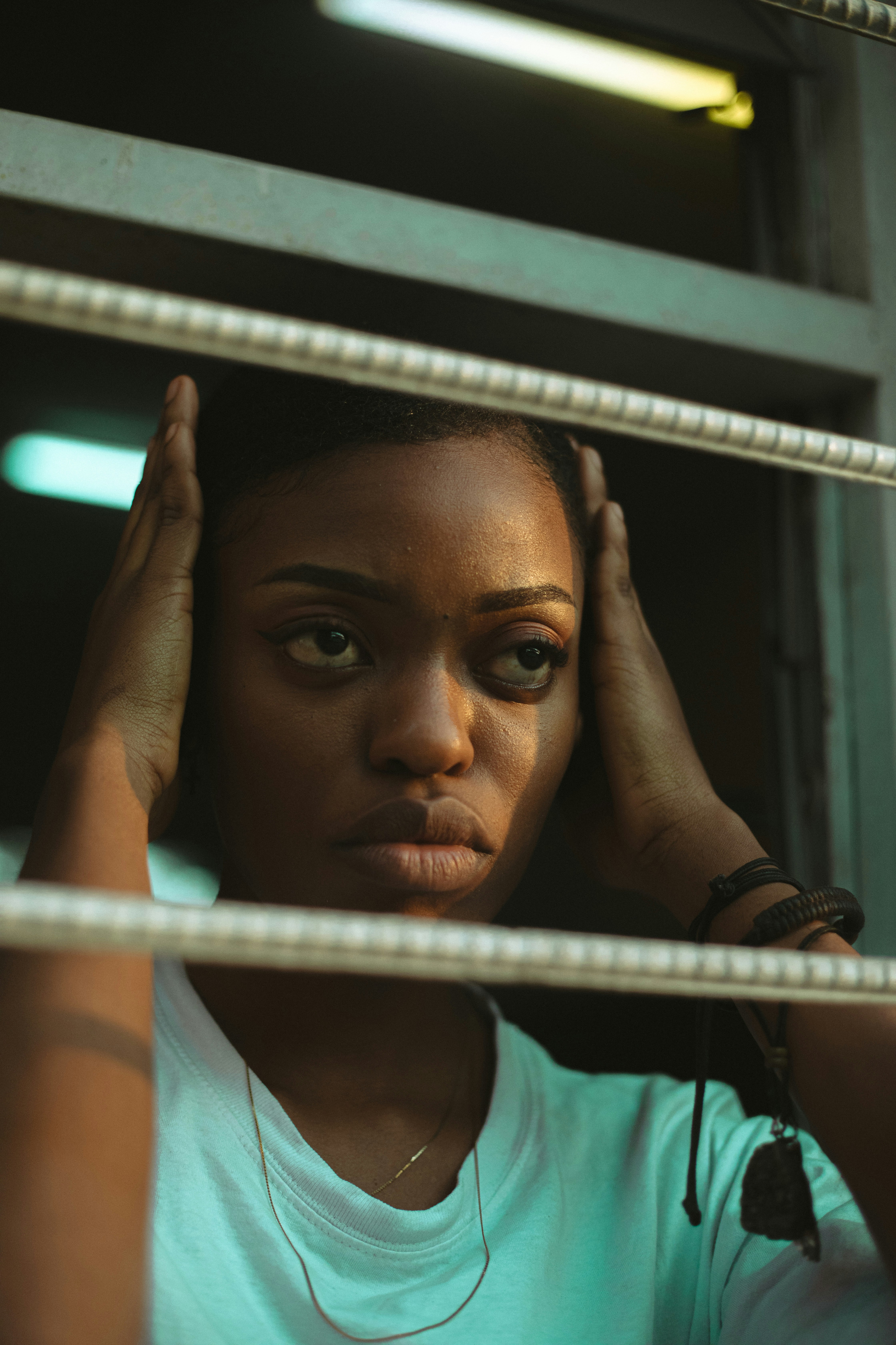 A woman looking out of a window with her hands on her head
