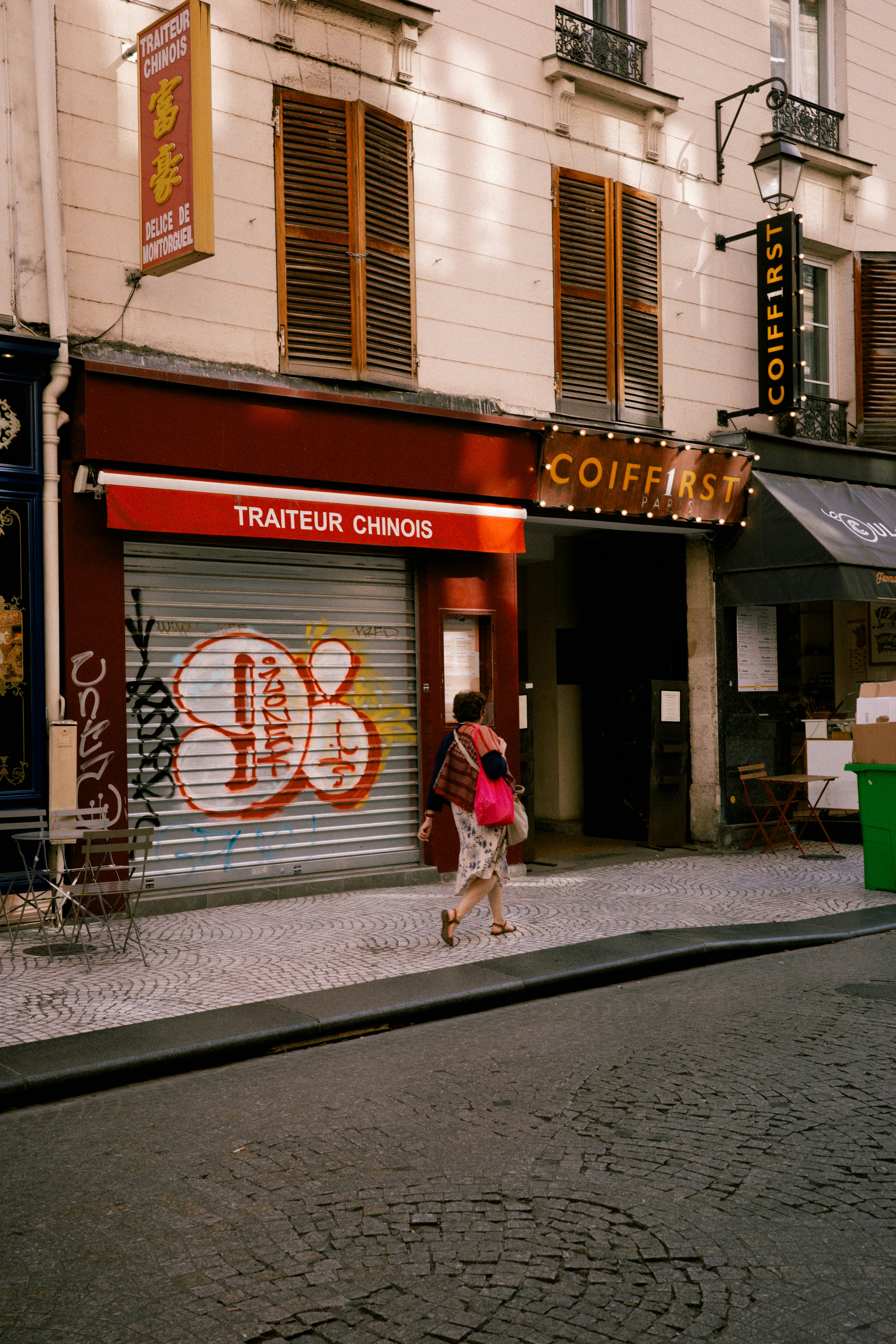 A woman walking down a street next to a tall building