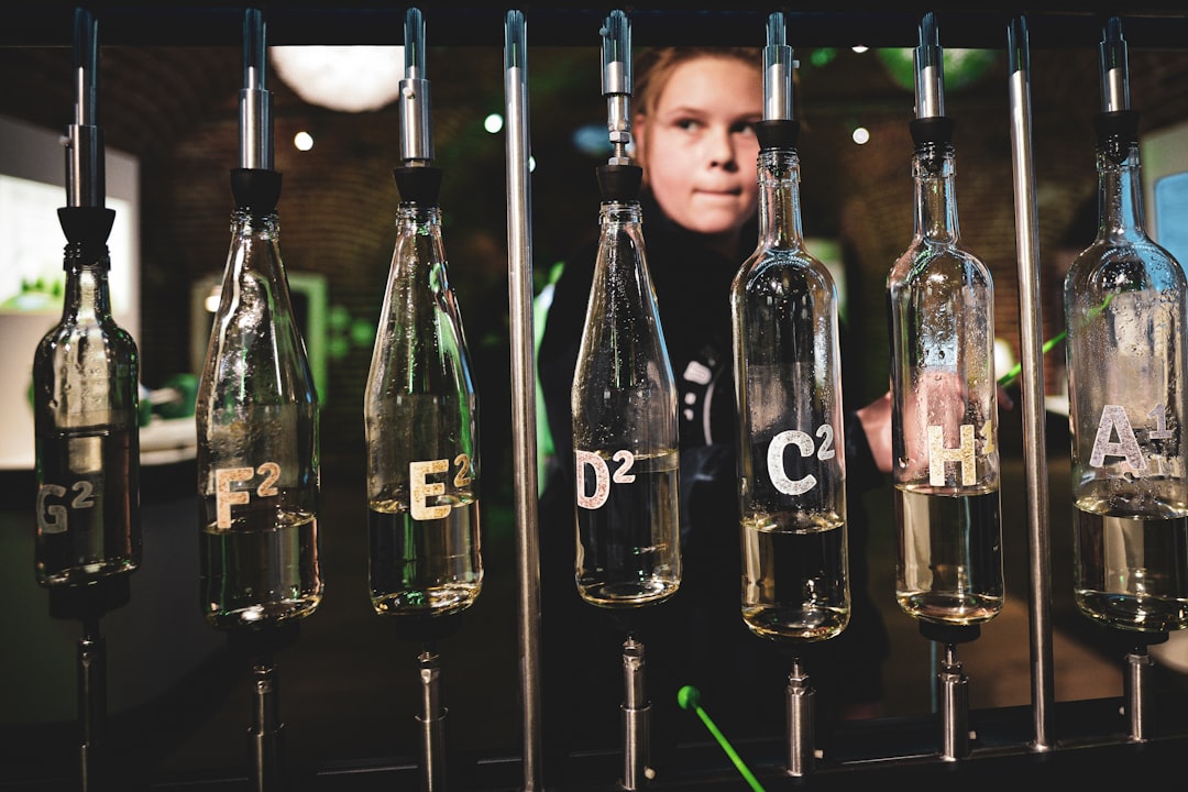 A man standing in front of a row of glass bottles,