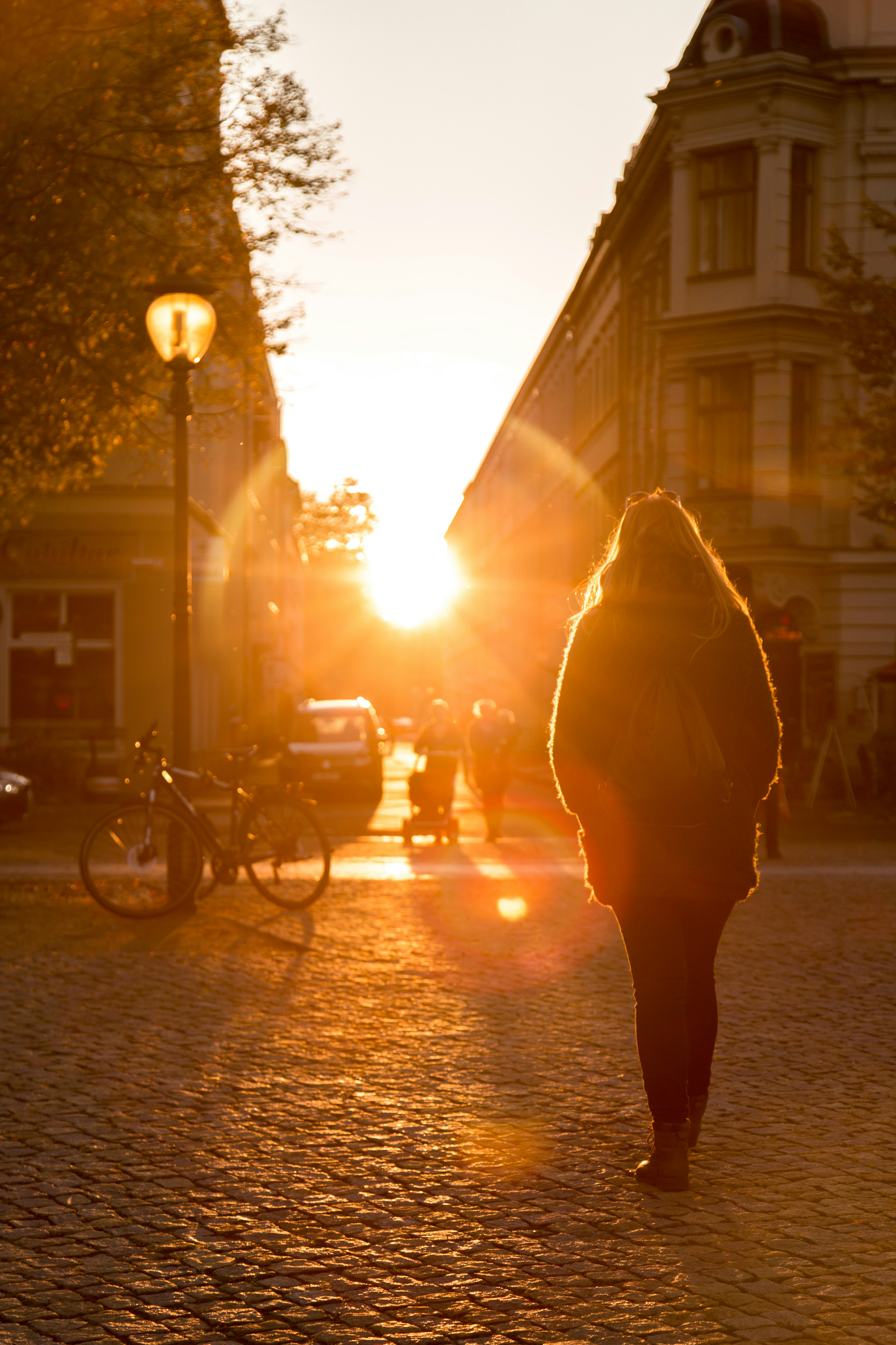 A person walking down a street at sunset