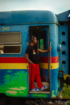 A man standing on the door of a colorful train
