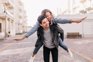 A man riding on the back of a woman on a skateboard