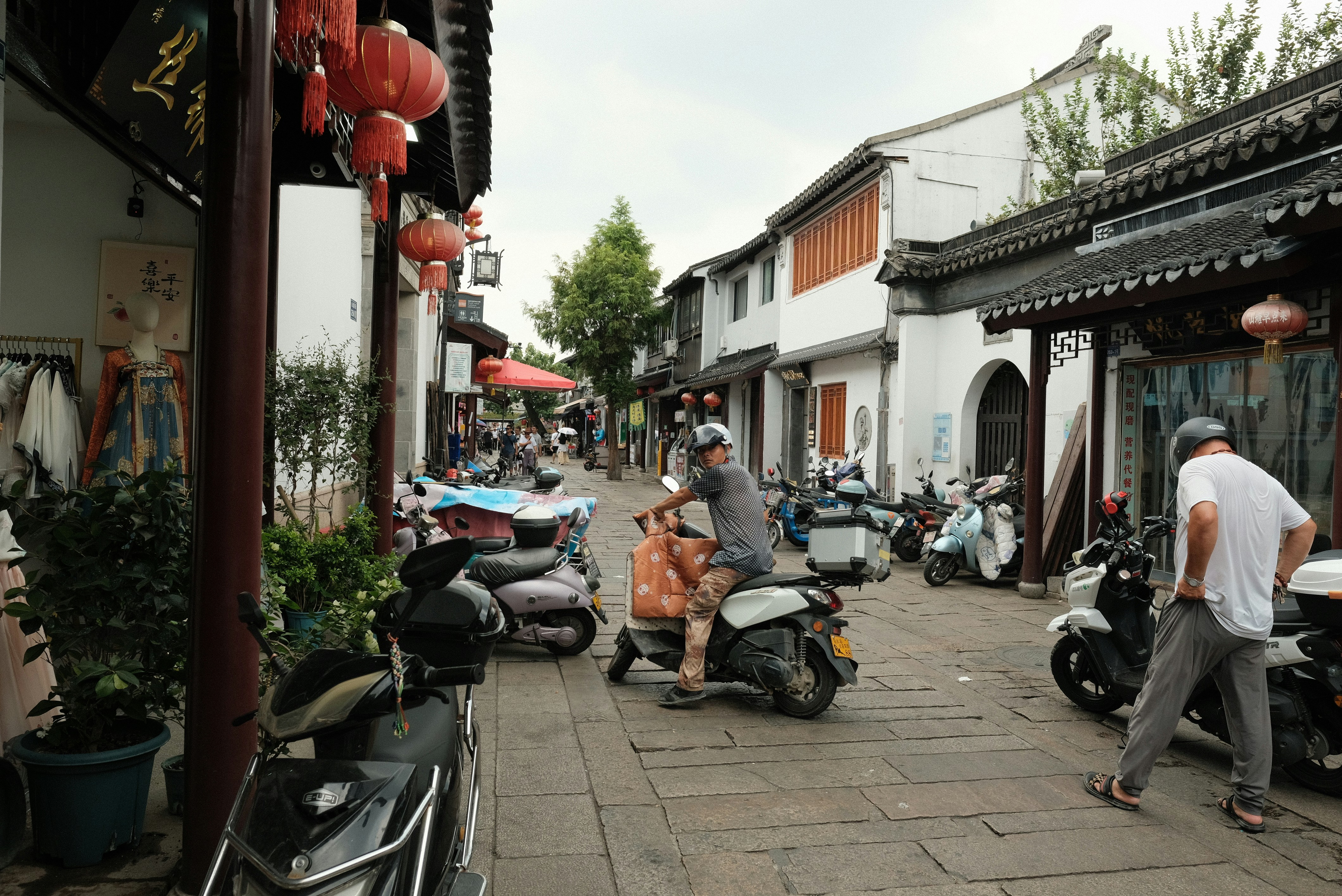 A group of people riding scooters down a street
