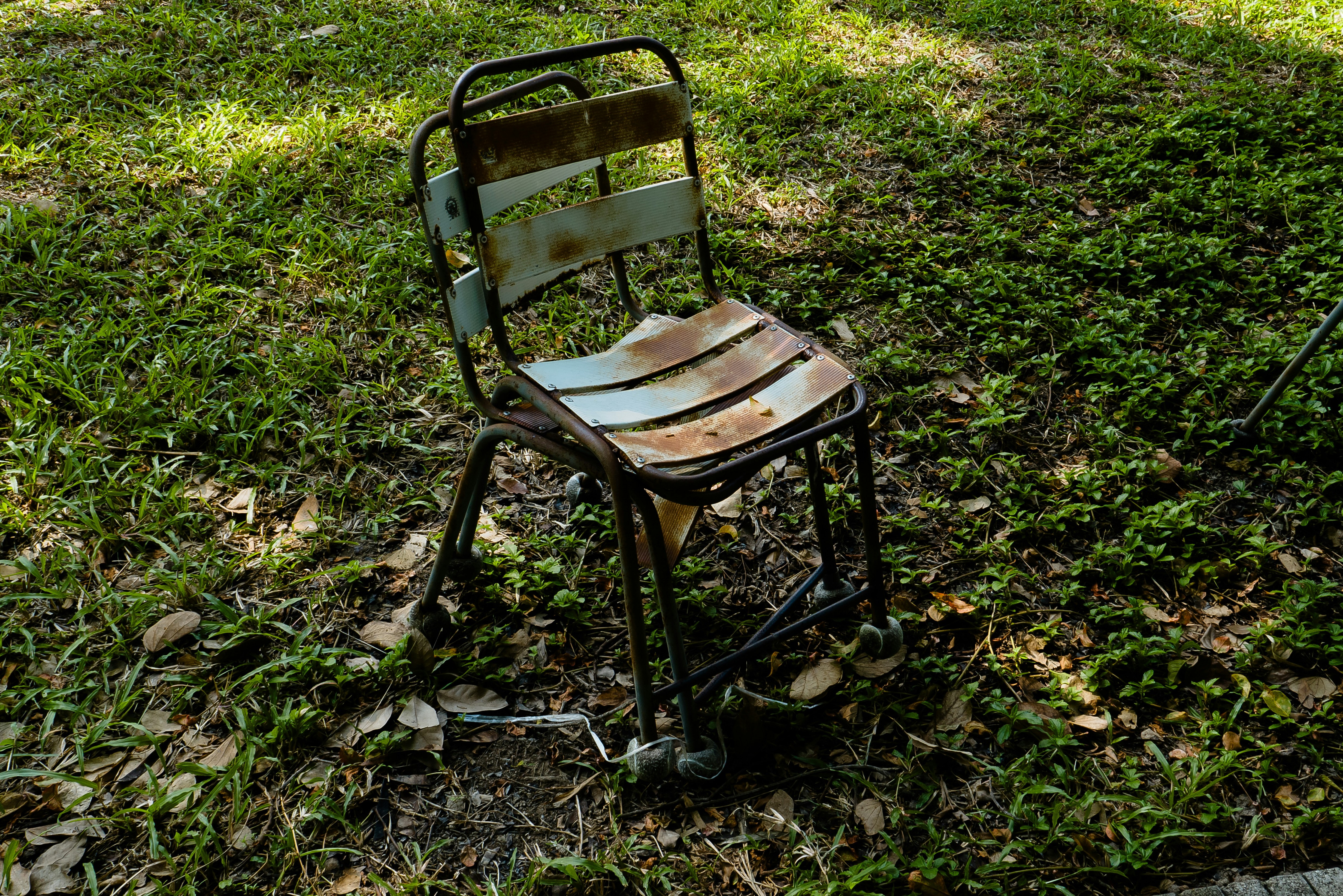 Metal bir sandalyedeki pas lekelerini temizlemek için fırça ve temizlik malzemeleri kullanan bir kişinin elleri.