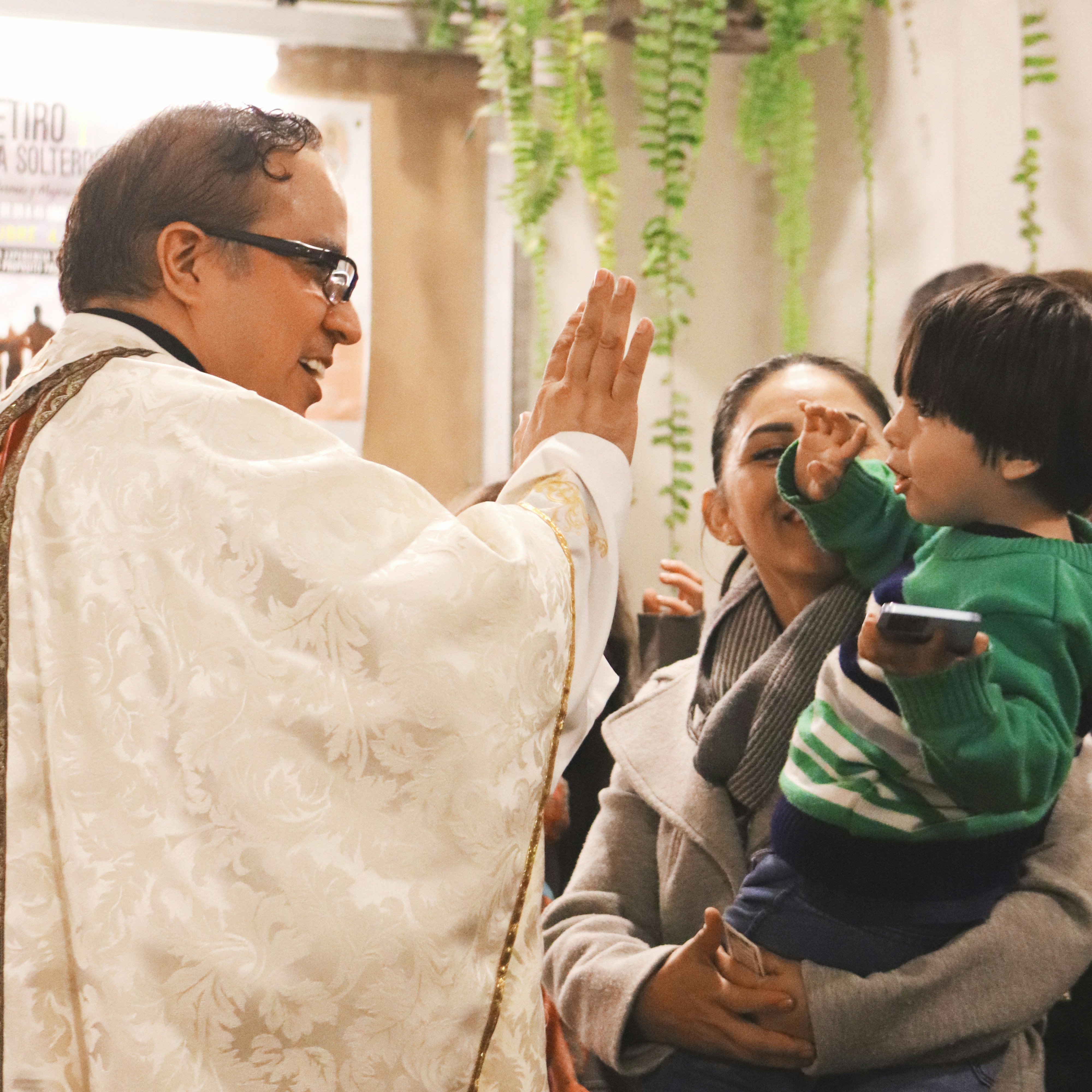 A man in a priest's robes is holding a child