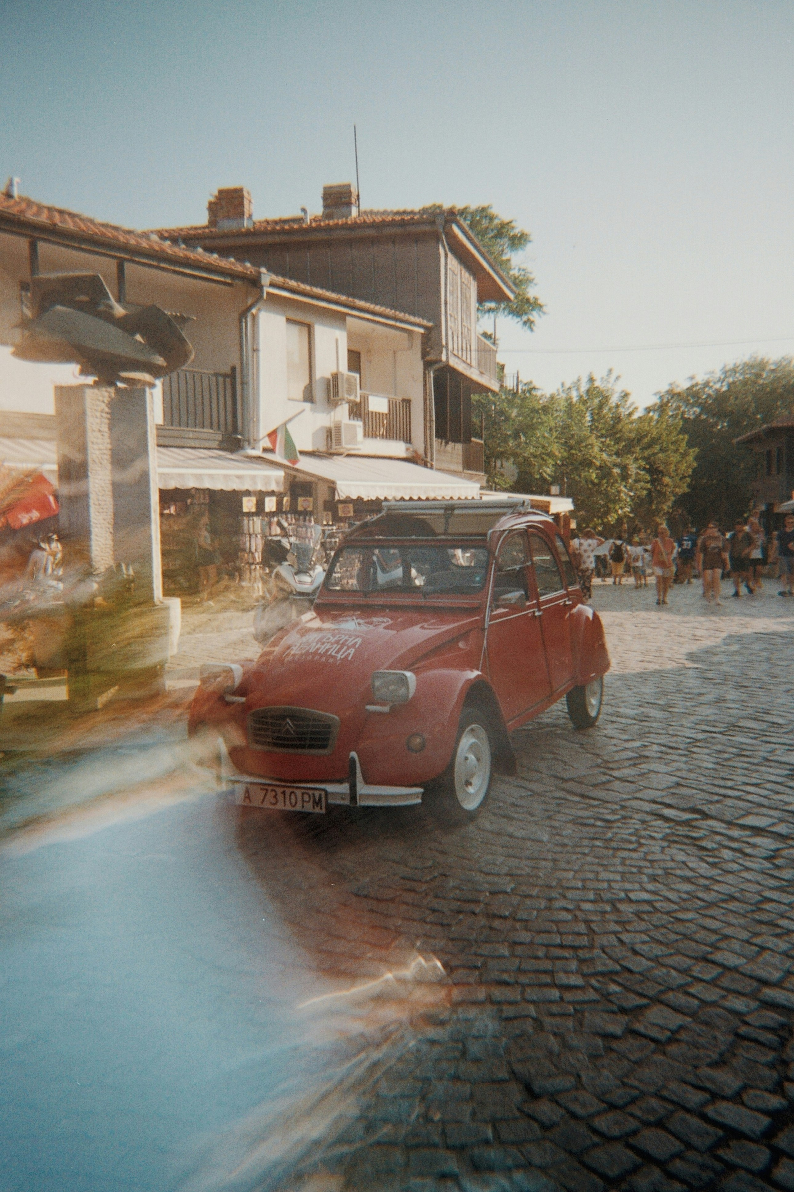 A red car driving down a cobblestone road