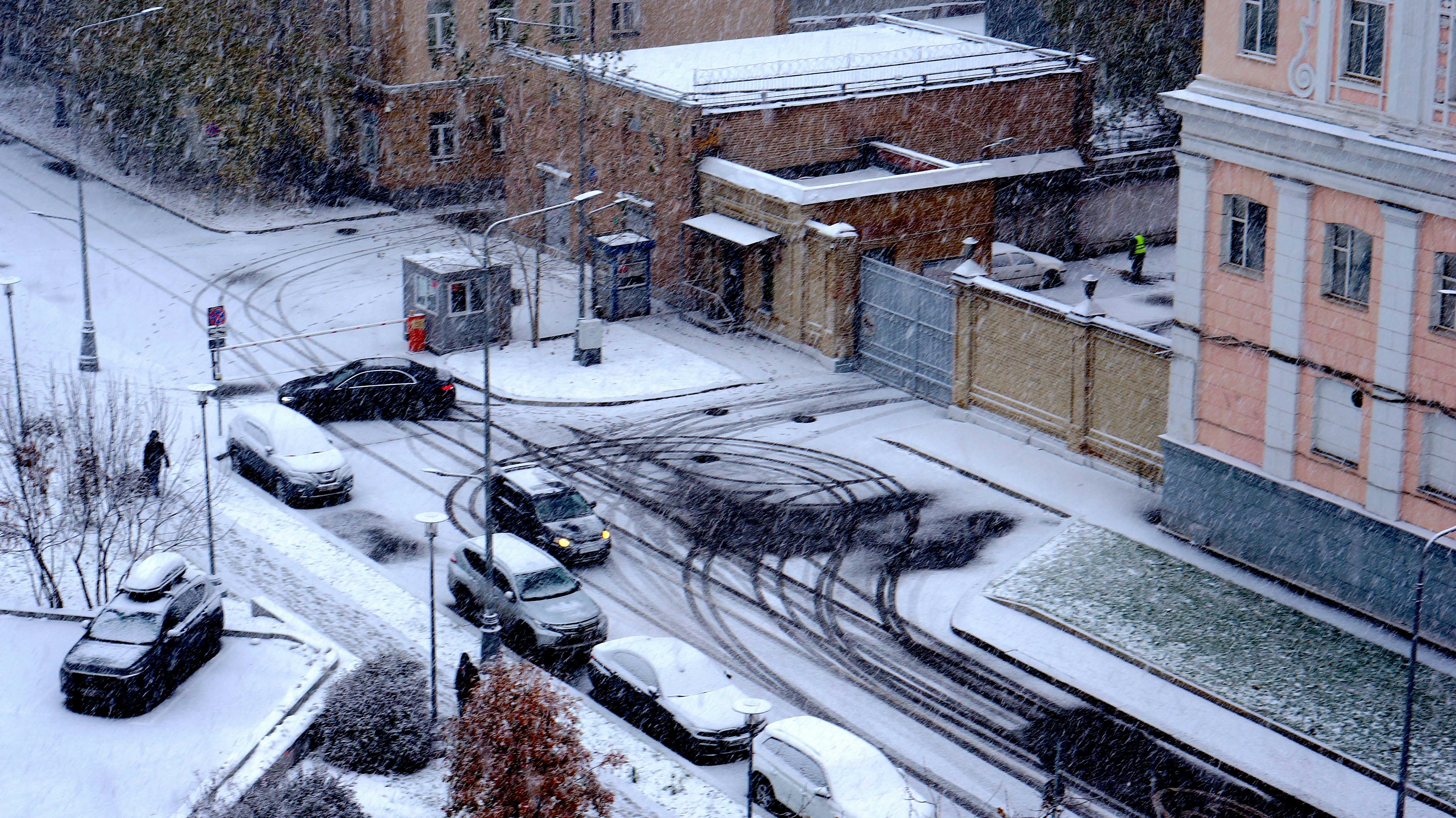 A snow covered city street with a train on the tracks