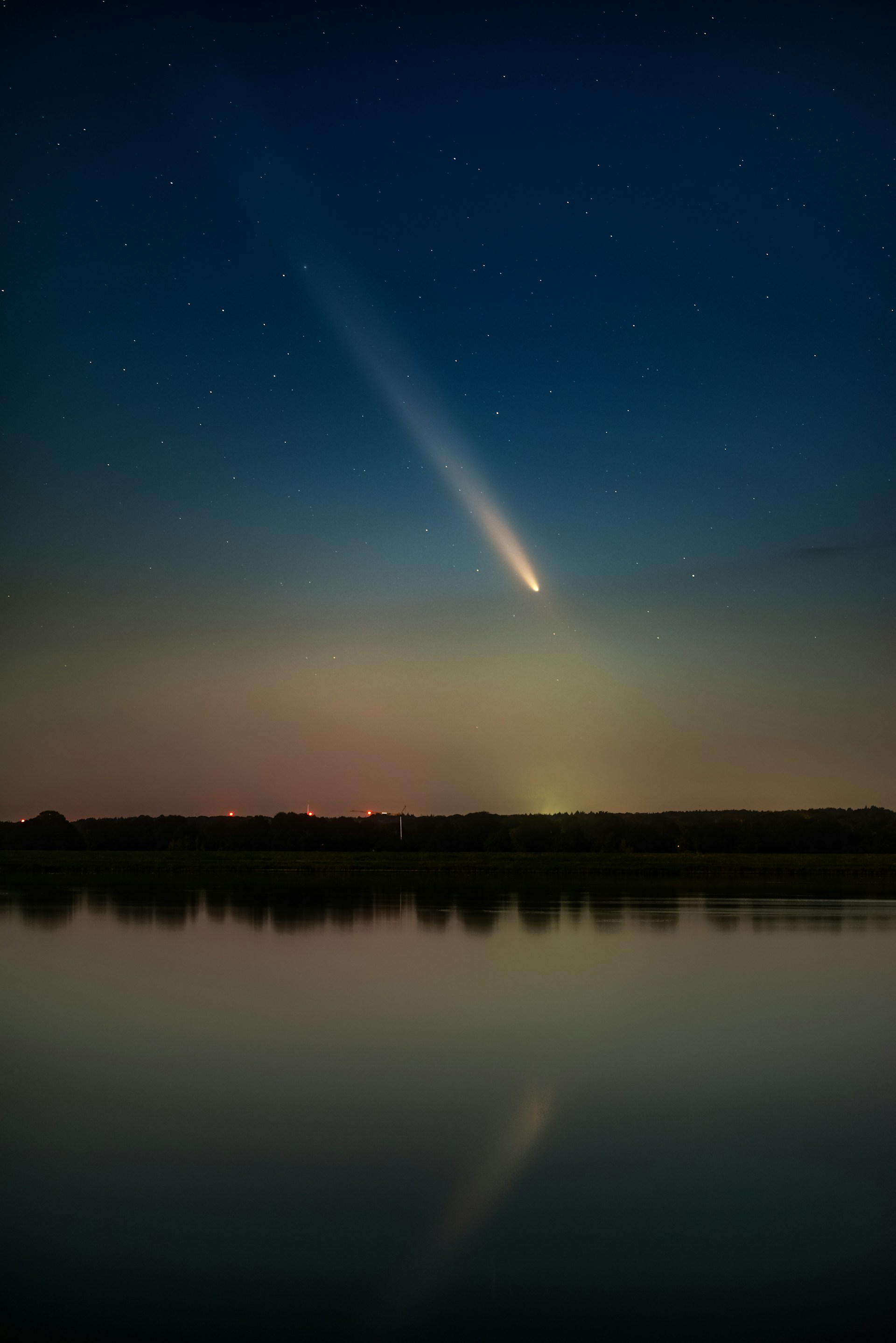 A comet is seen in the sky above a lake