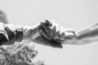 A black and white photo of two people holding hands