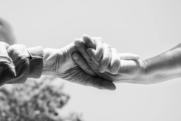 A black and white photo of two people holding hands