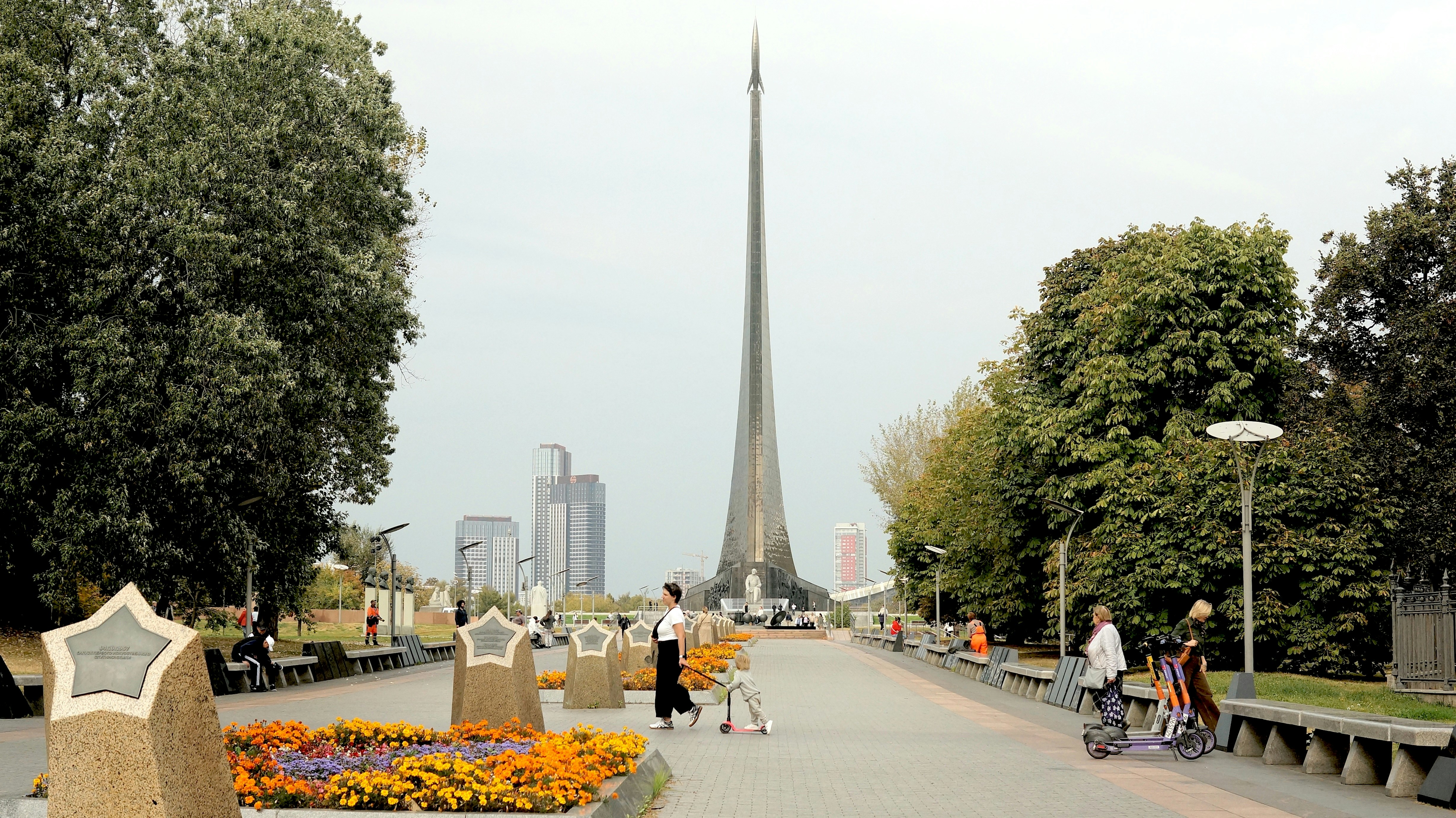 A park with benches, flowers, and people walking