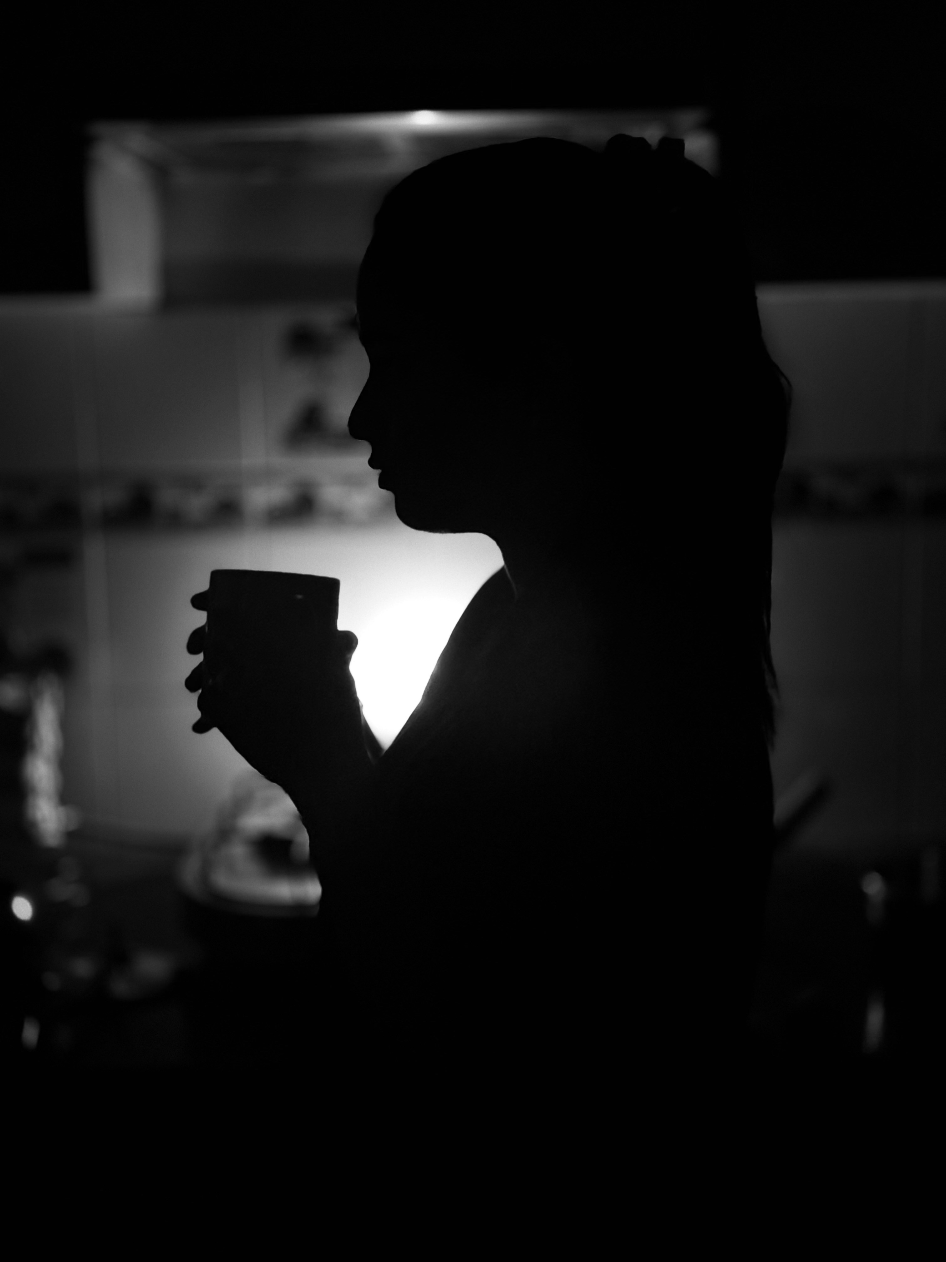 A silhouette of a woman holding a cup of coffee