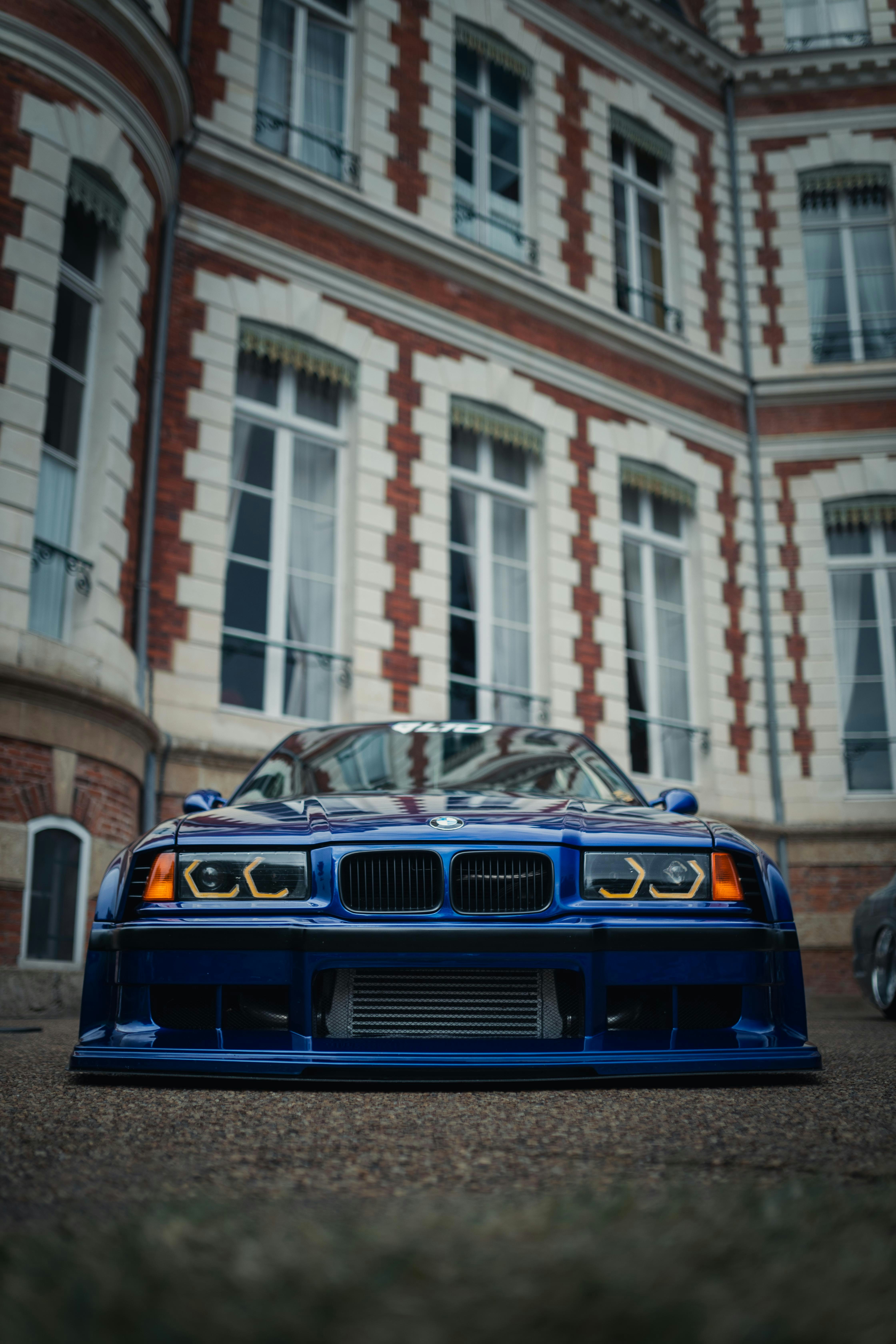A blue car parked in front of a tall building