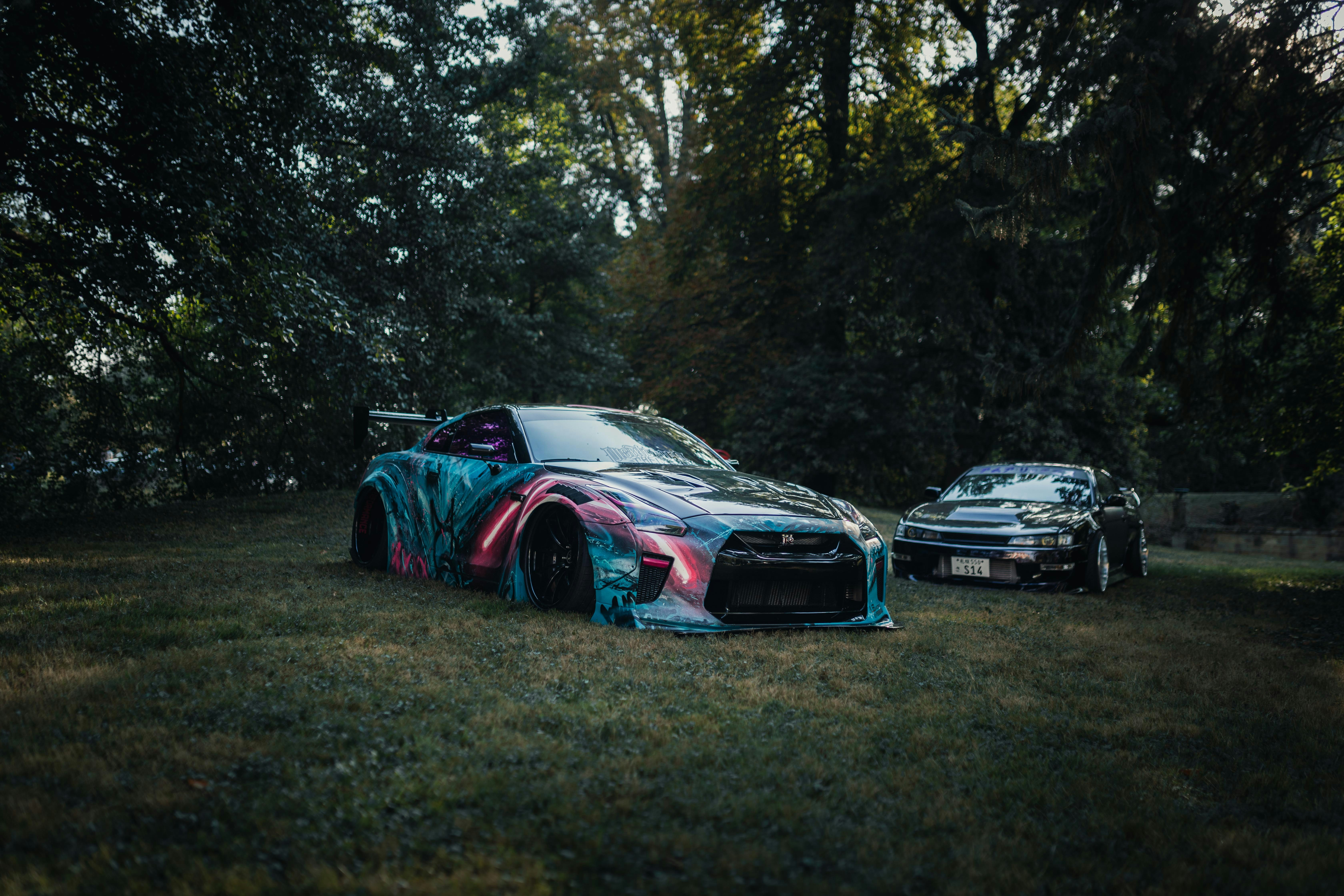 Two cars parked in the grass near trees