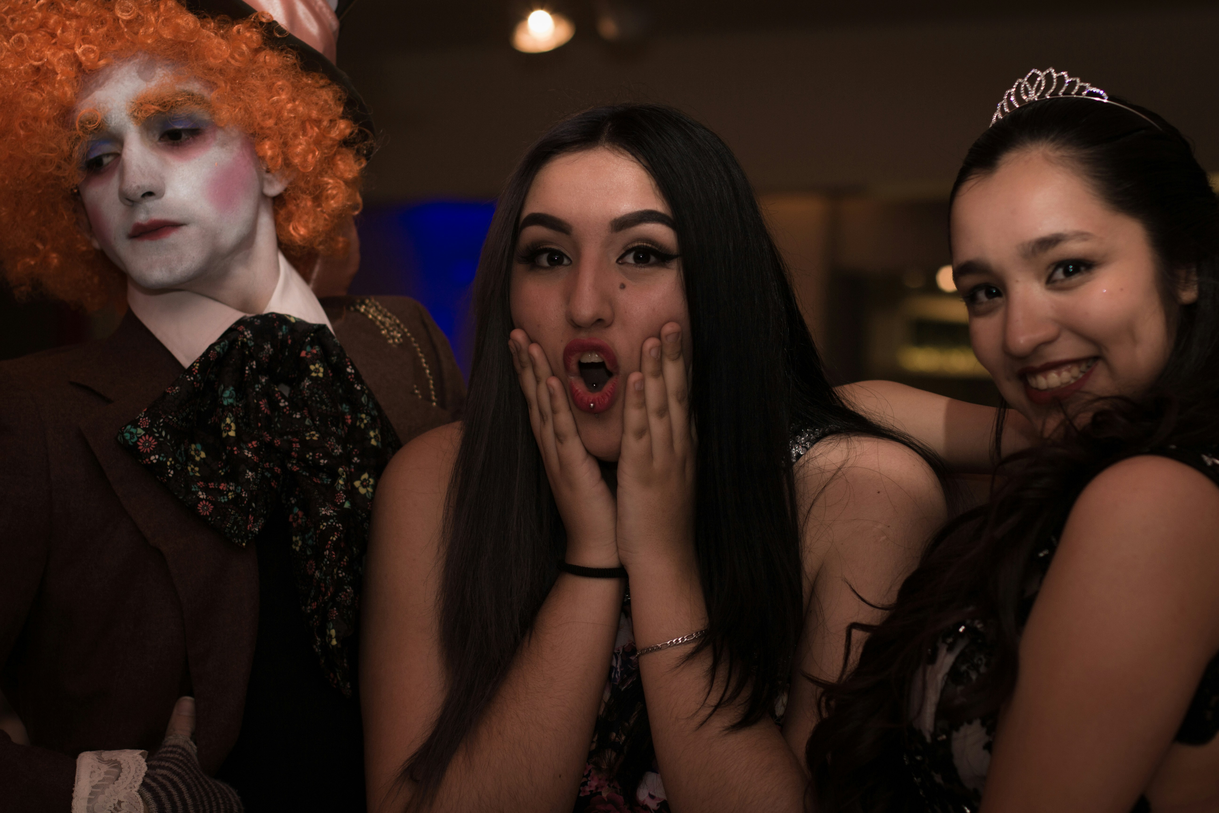 A diverse group of drag queens backstage, helping each other with makeup and costumes, laughing and sharing a moment.