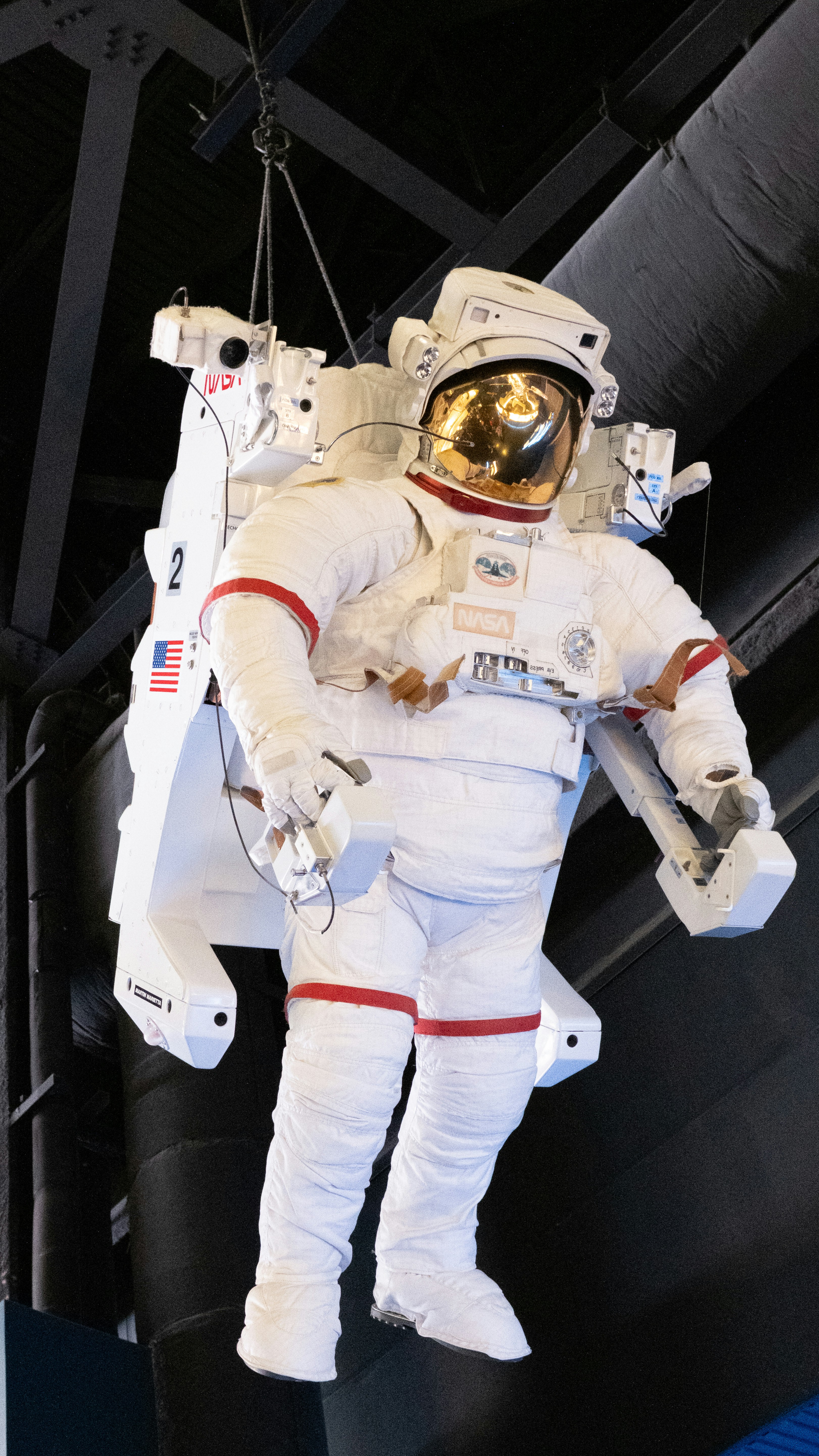 A man in a space suit suspended from a ceiling