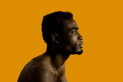 Man in profile on a burnt orange backdrop