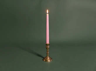 A single pink candle sitting on top of a table