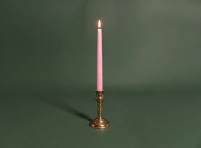 A single pink candle sitting on top of a table
