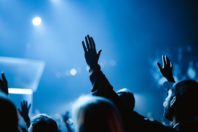 A crowd of people at a concert raising their hands