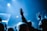 A crowd of people at a concert raising their hands