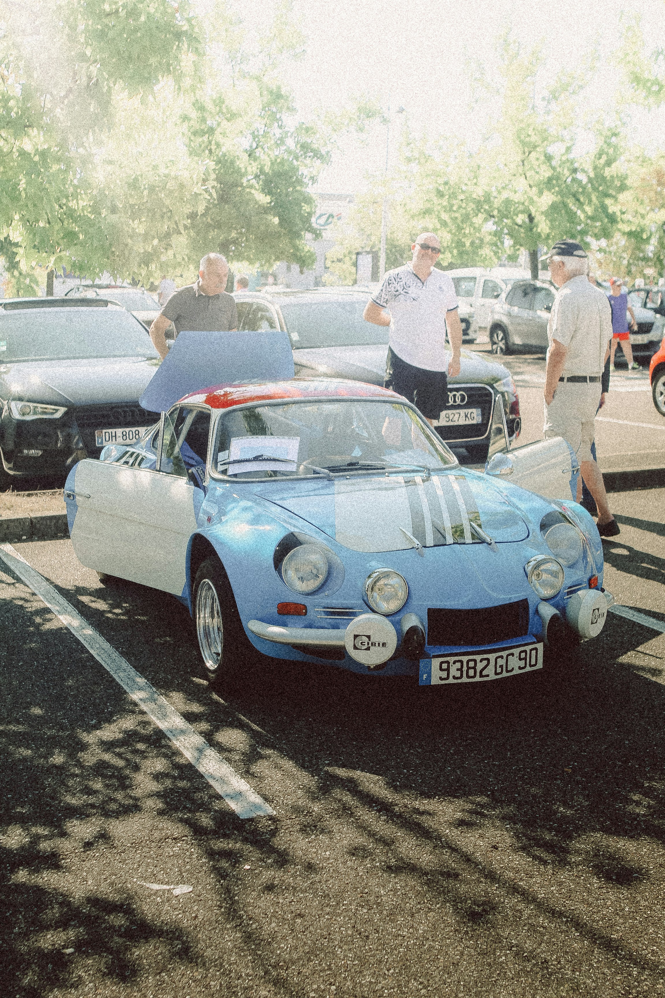 A blue car parked in a parking lot next to other cars