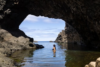 A person standing in a body of water near rocks