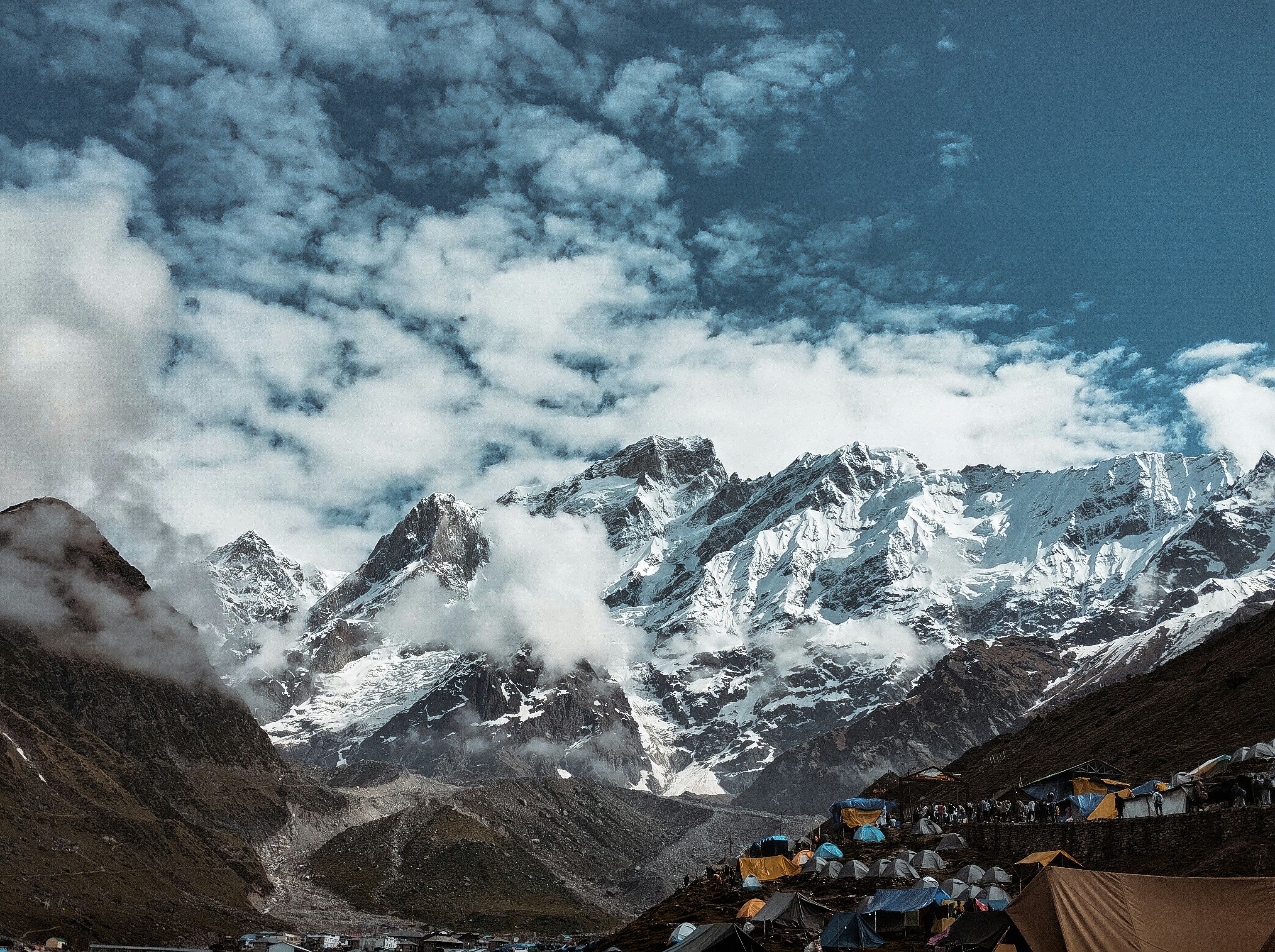 A group of tents in the mountains under a cloudy sky