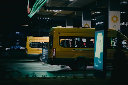 A yellow van parked in a parking lot at night