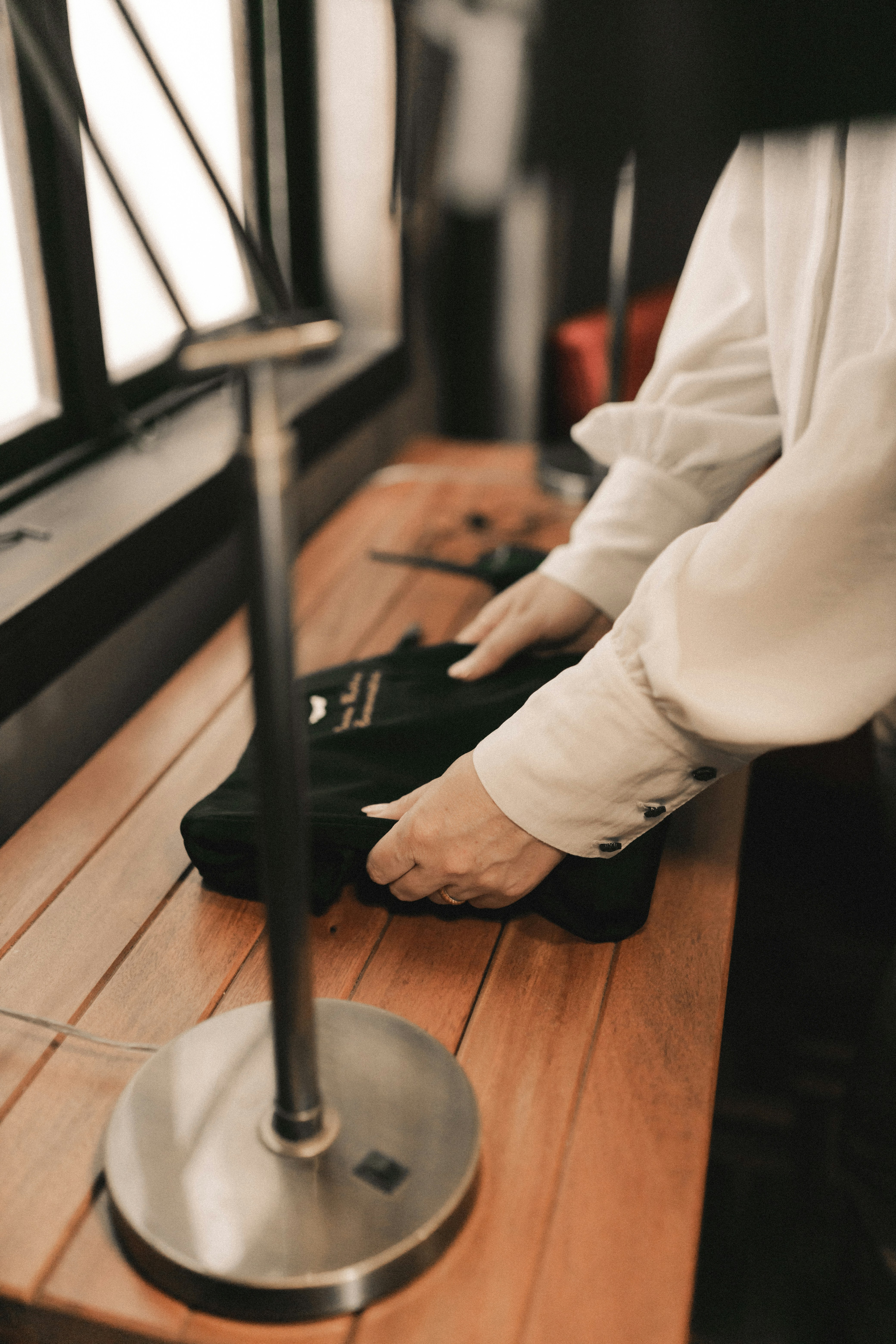 A person standing on a wooden table with a pair of black shoes