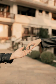 A man in a leather jacket is giving another man a hand