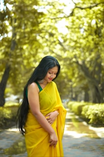 A woman in a yellow sari walking down a path