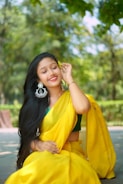 A woman in a yellow sari sitting on the ground