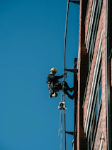 A man on a high wire working on a building
