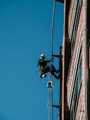 A man on a high wire working on a building