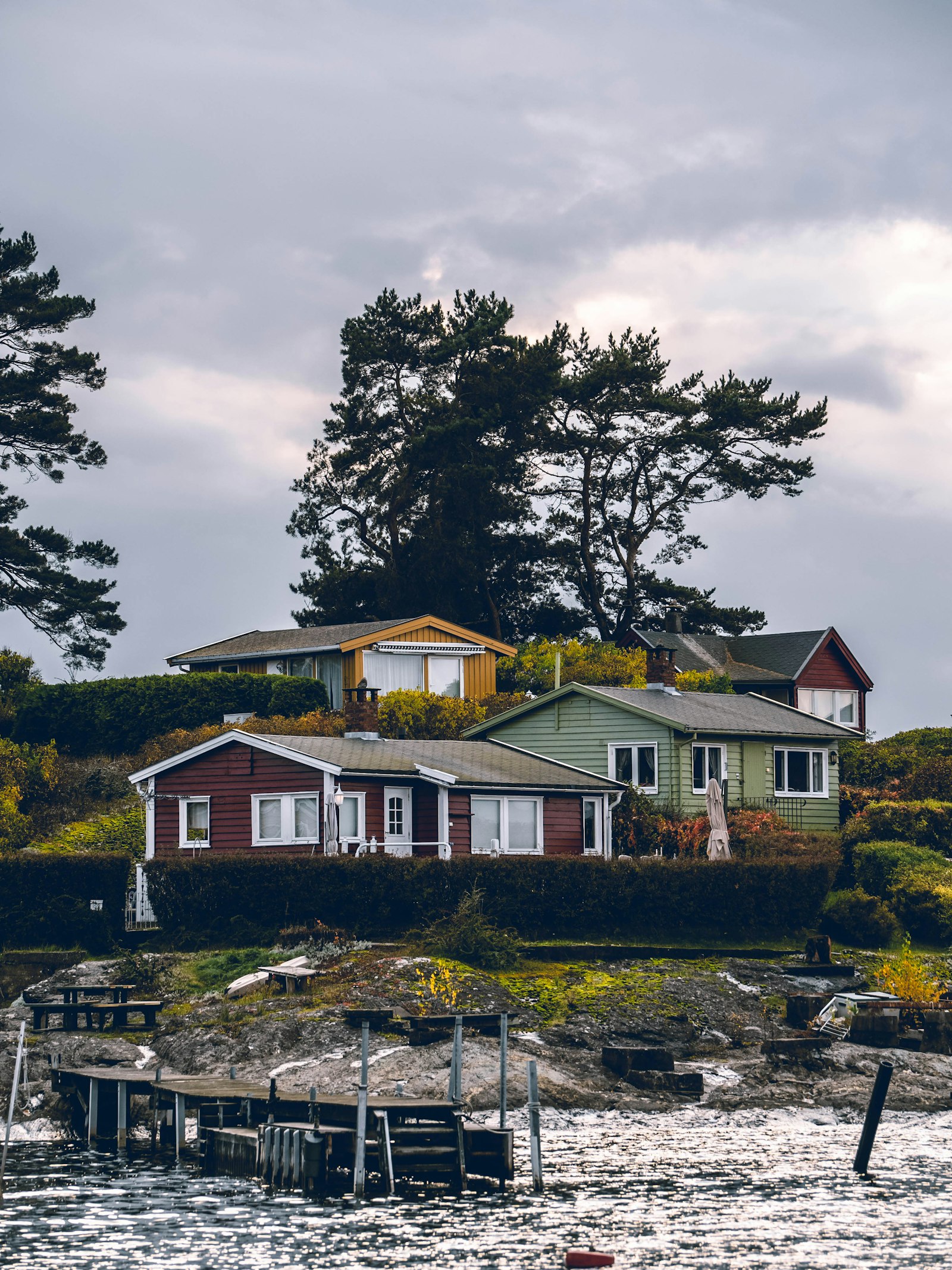 A cluster of modest waterfront cottages on a rocky shore above old timber docks