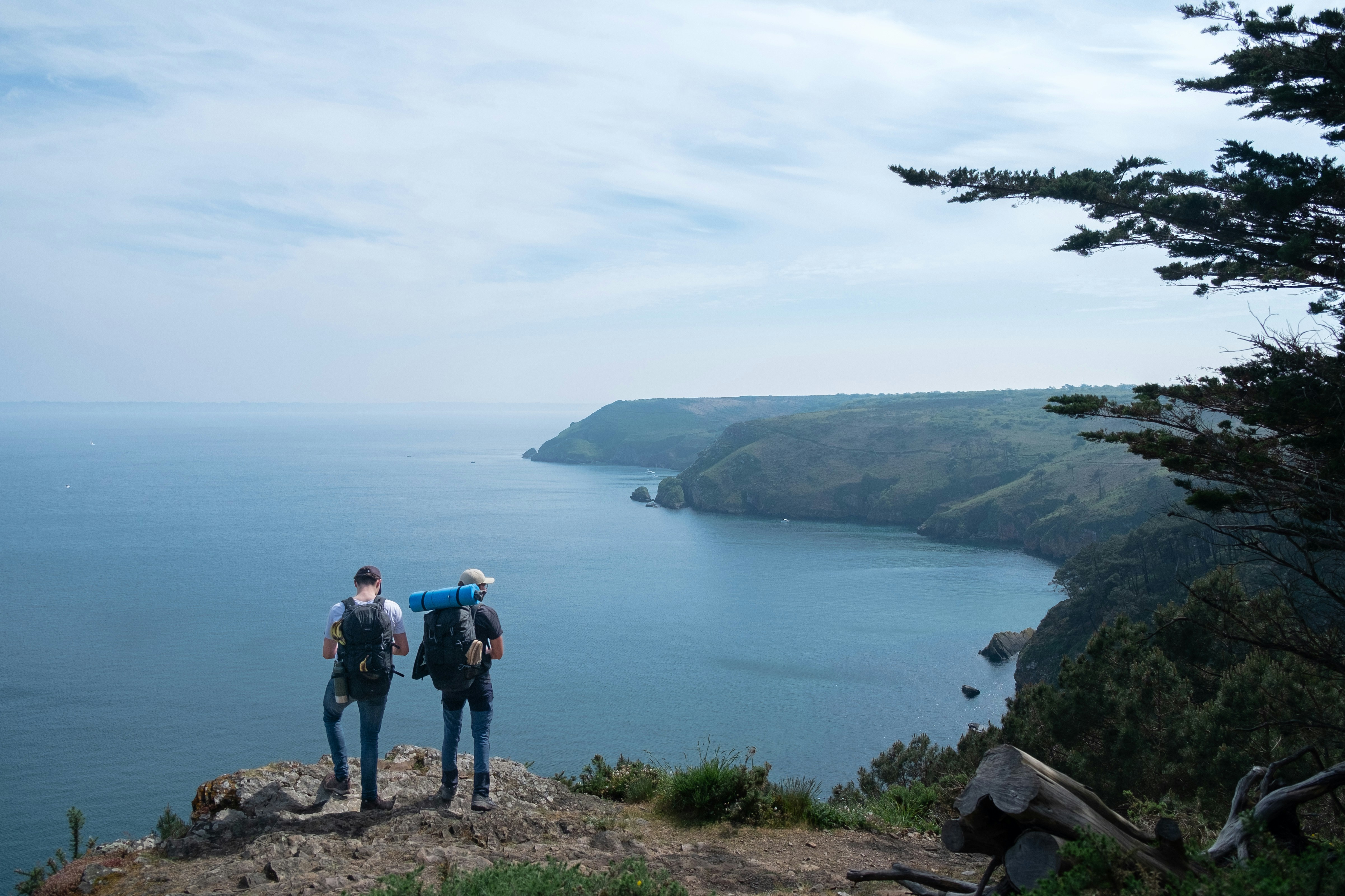 Young traveler with backpack standing on cliff overlooking Australian coastal scenery