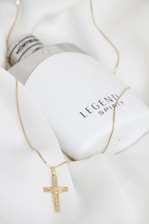A bottle of lotion and a gold cross necklace