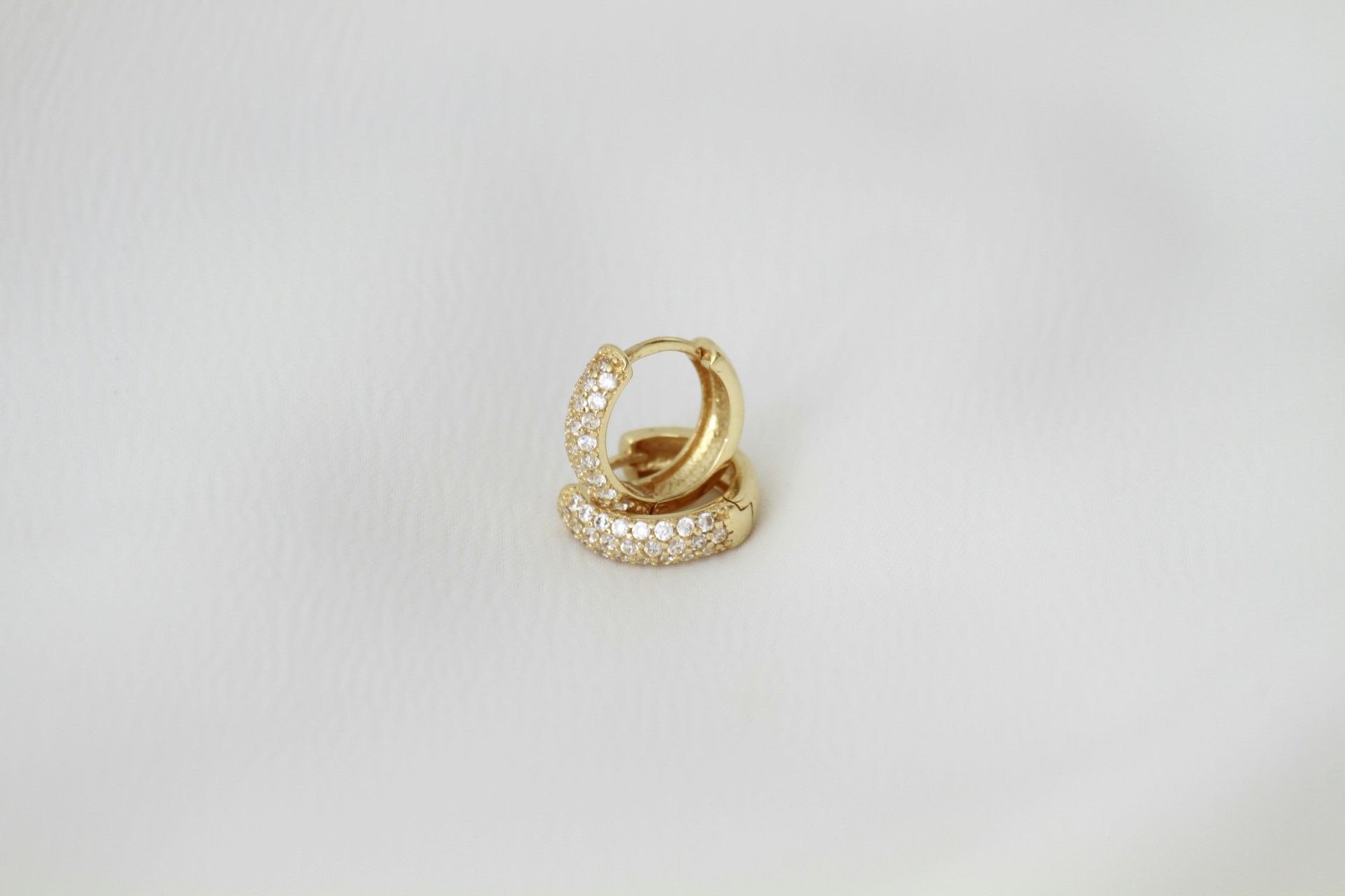 A pair of gold hoop earrings on a white background