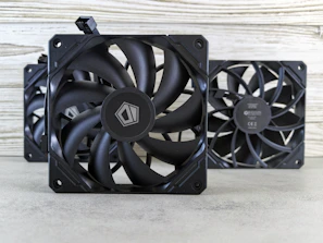 A couple of black fans sitting on top of a table