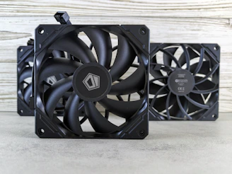 A couple of black fans sitting on top of a table