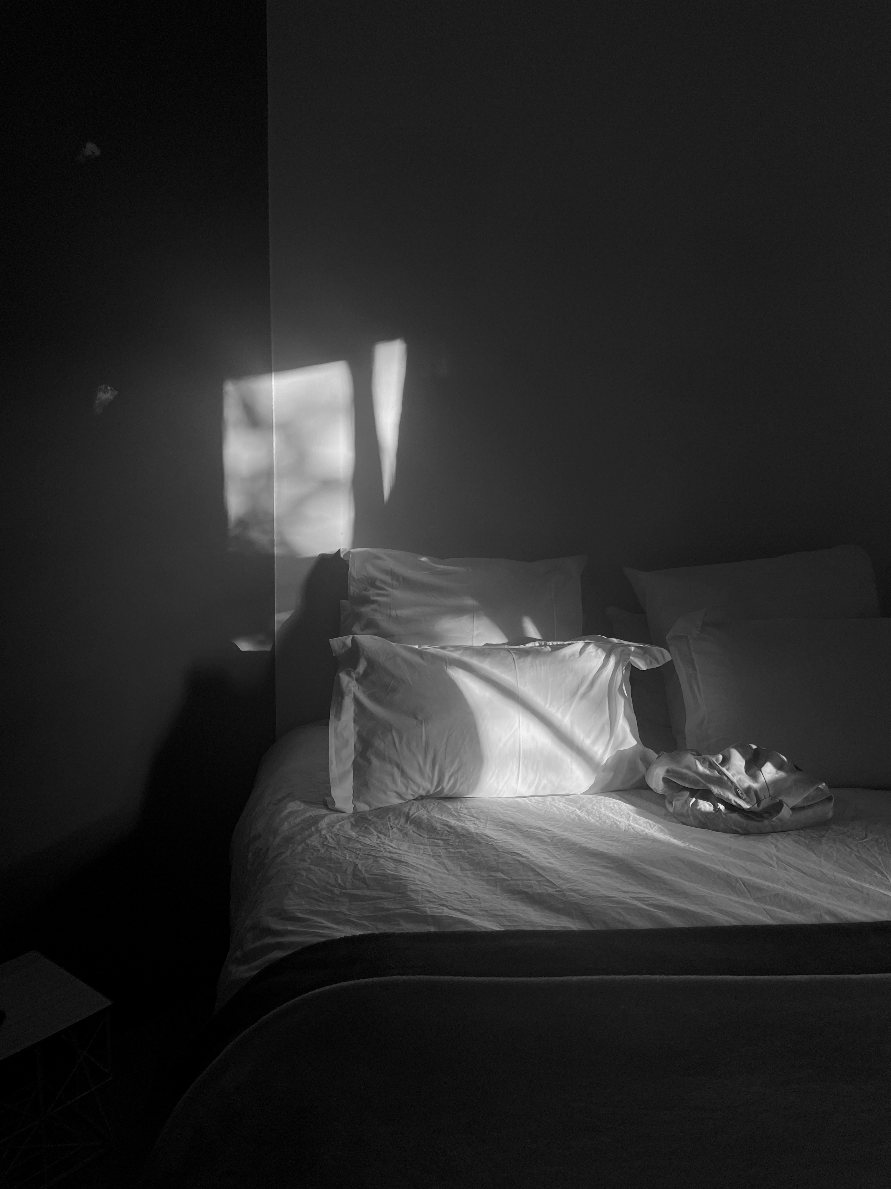 A black and white photo of a bed in a dark room