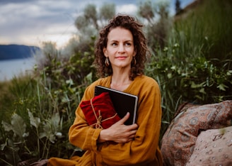 A woman sitting on a rock holding a book