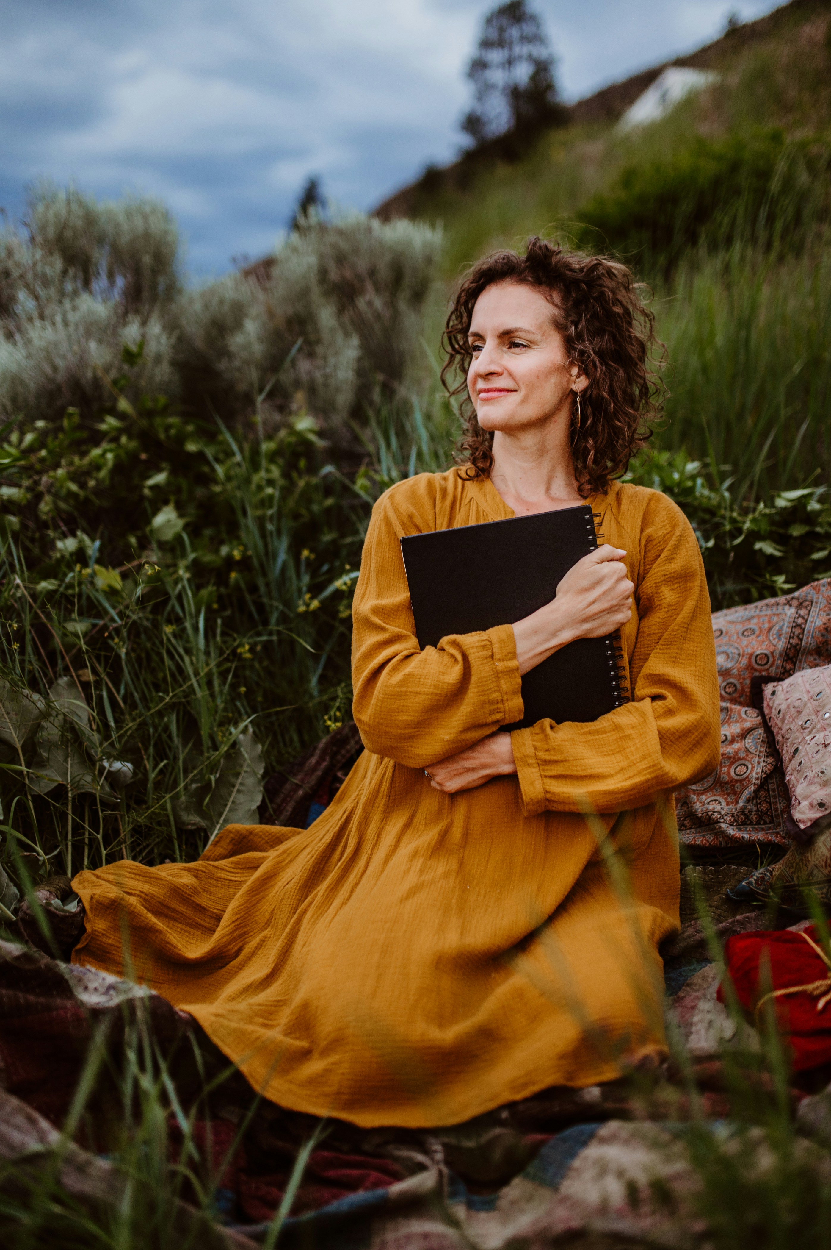 A woman in a yellow dress sitting on rocks