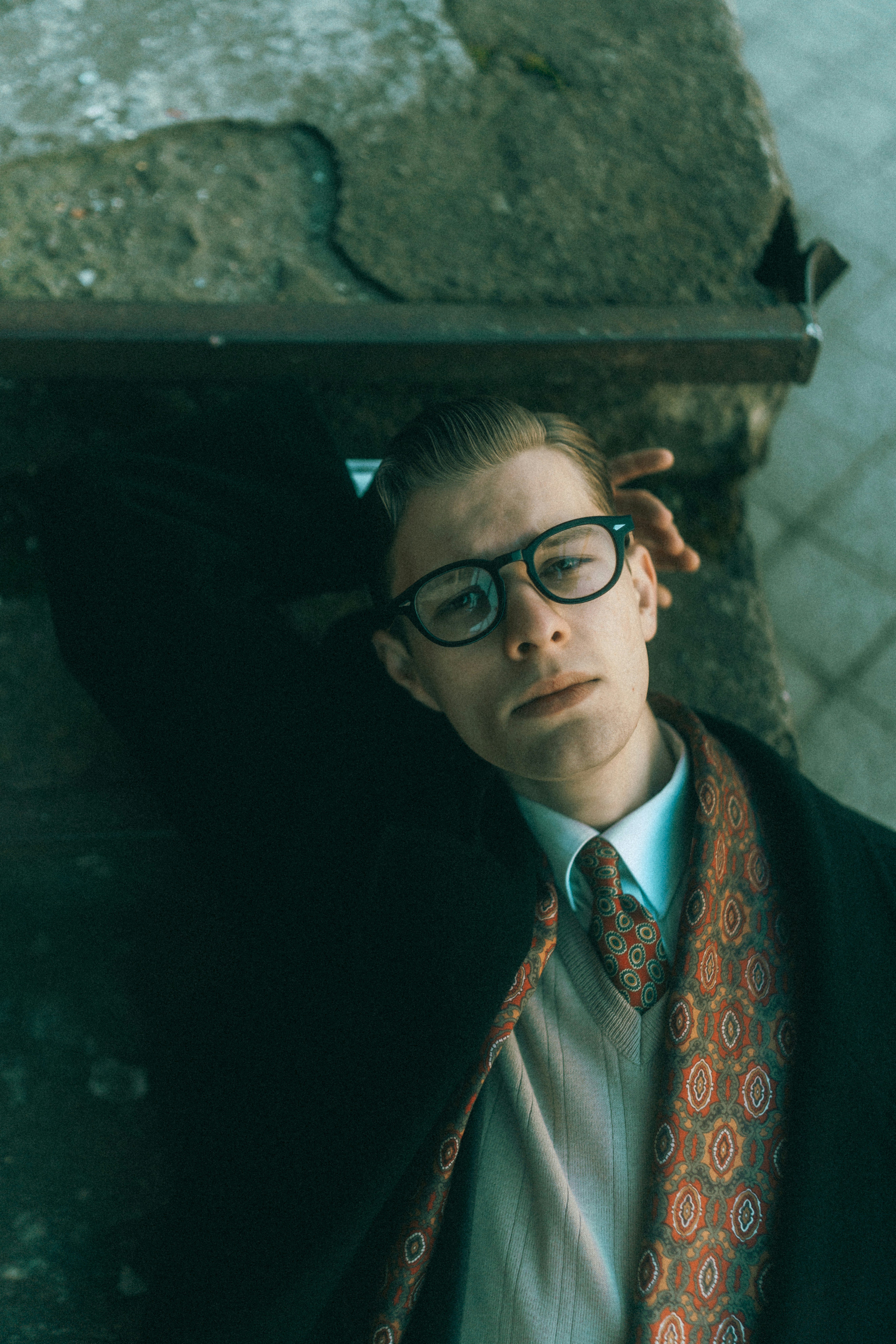 A man in a suit and tie leaning against a wall
