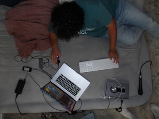 A person laying on a bed with a laptop