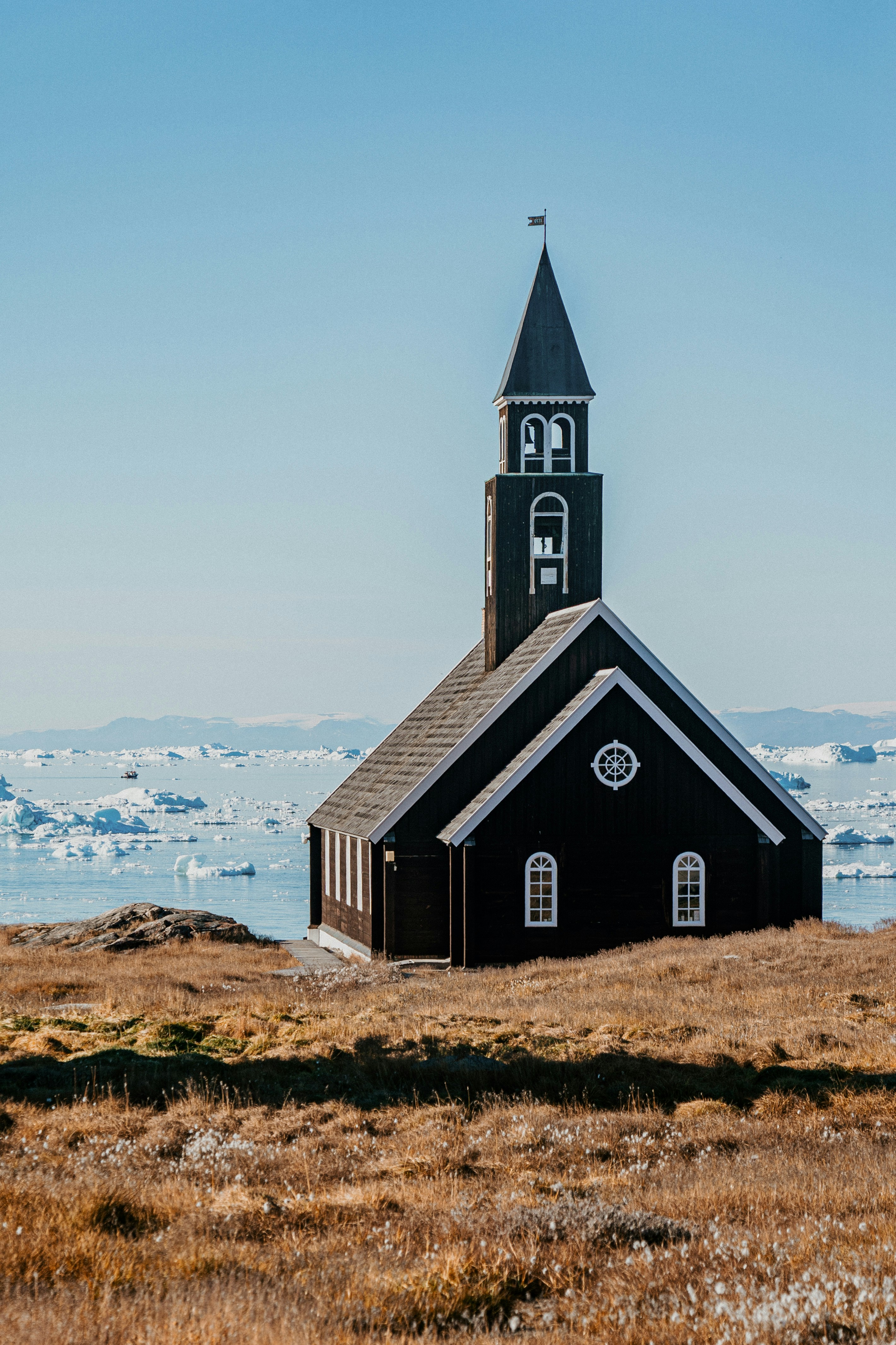 A small black church with a steeple on top of it